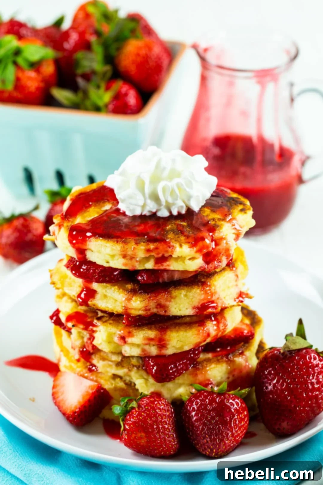 Close-up stack of golden-brown pancakes generously covered in glistening strawberry syrup.