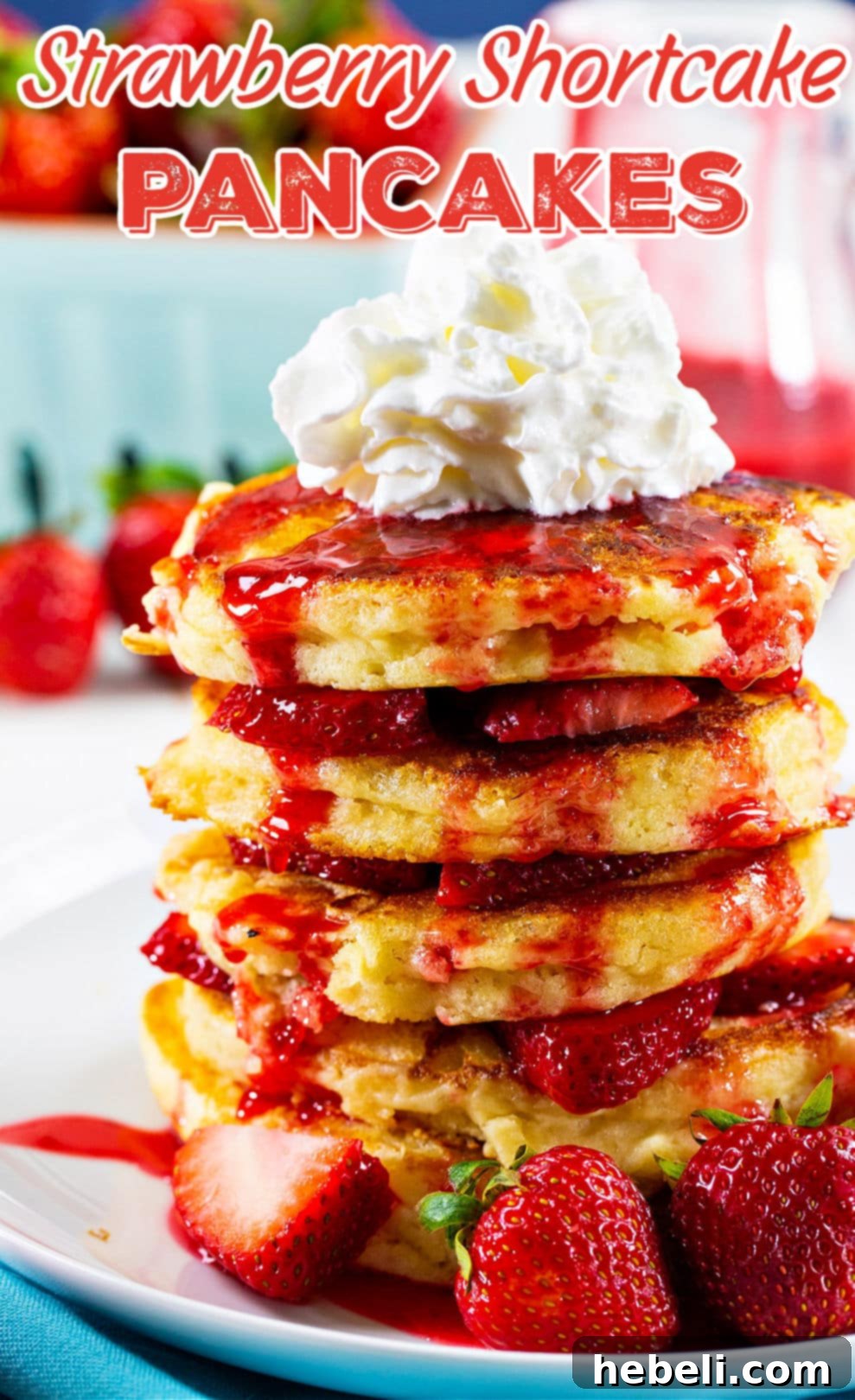 Another beautiful stack of strawberry pancakes garnished with fresh whipped cream and a sprinkle of powdered sugar.