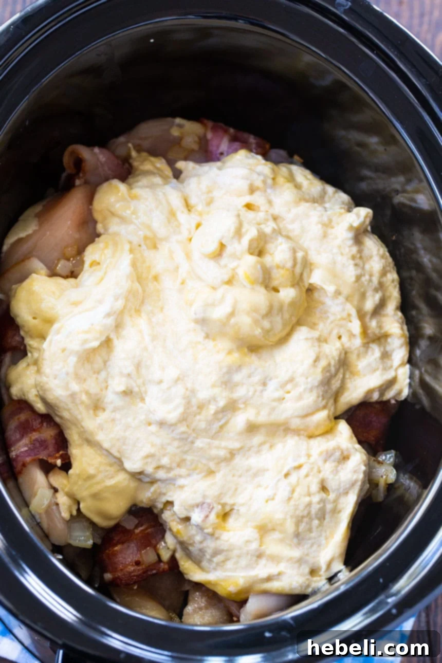 Mixing bowl with sour cream, condensed soups, and seasonings, ready to be poured over chicken.