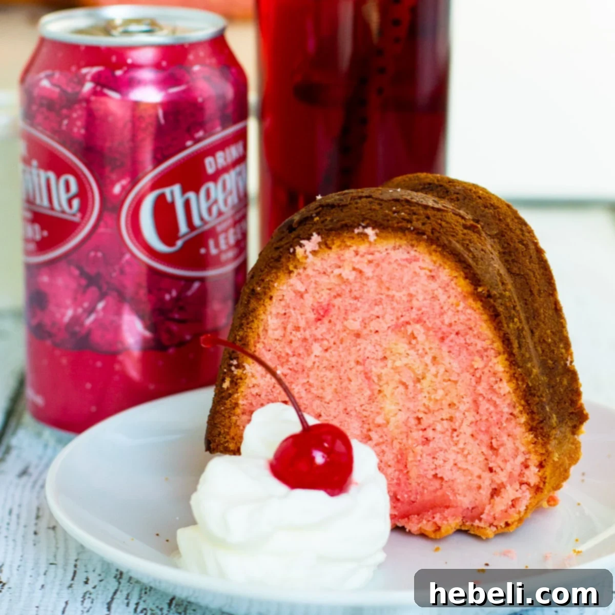 Slice of Cheerwine Bundt Cake on a plate next to a can of Cheerwine, showcasing its vibrant pink hue.