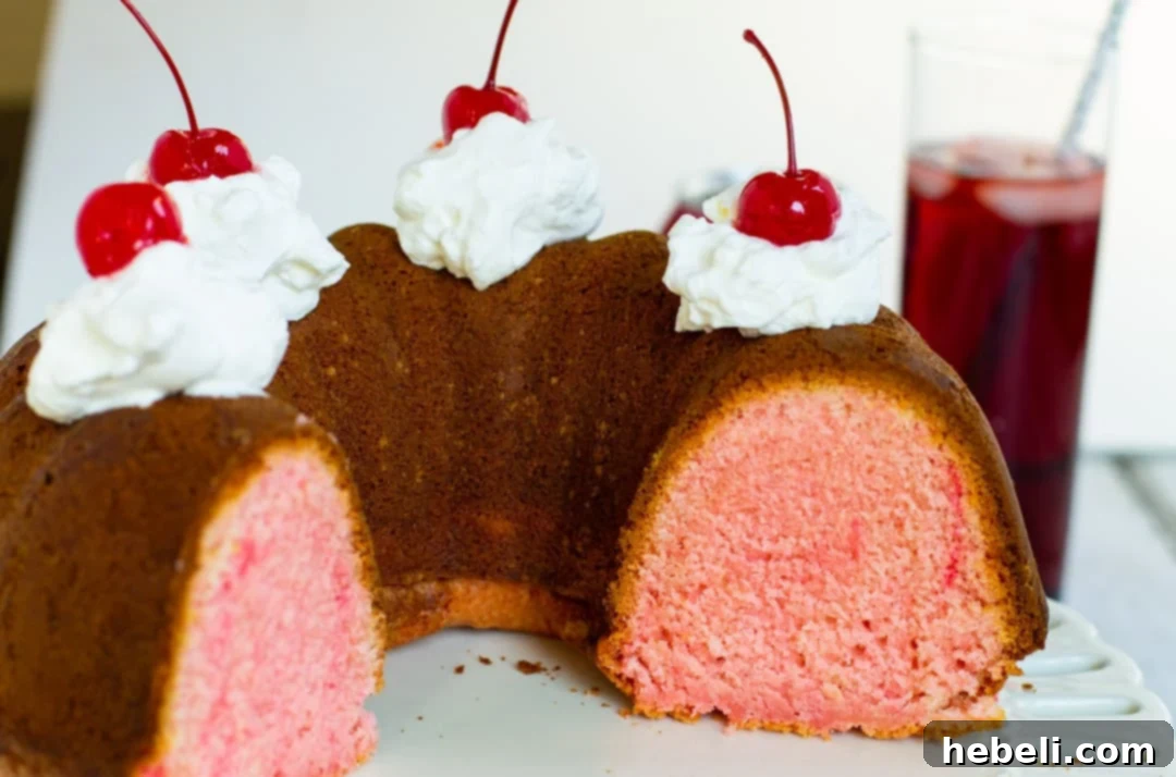 Cheerwine Bundt Cake adorned with a cloud of whipped cream and vibrant maraschino cherries.