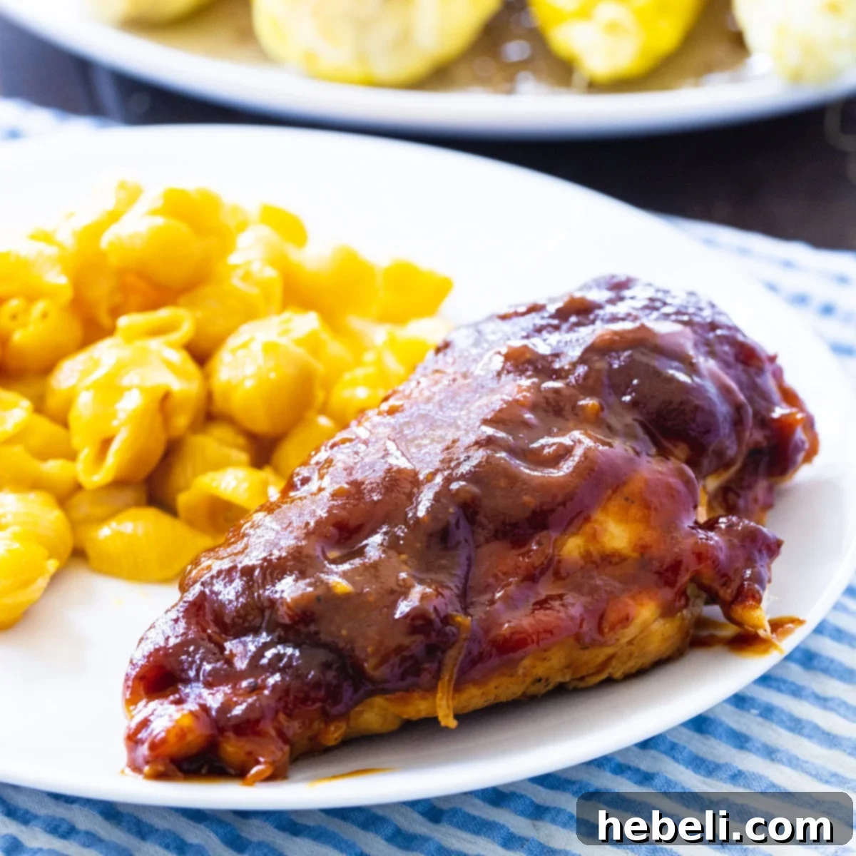 Sweet and Tangy Oven-Barbecued Chicken on a plate with mac and cheese, ready to be enjoyed.