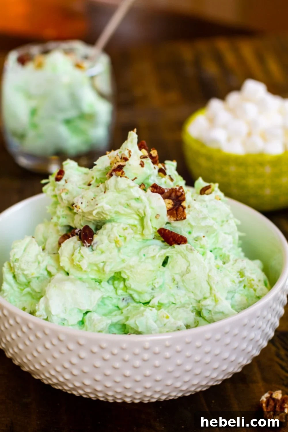 A close-up view of a large bowl of fluffy, light green Watergate Salad, showcasing its airy texture, visible marshmallow bits, and the subtle sparkle of whipped topping.