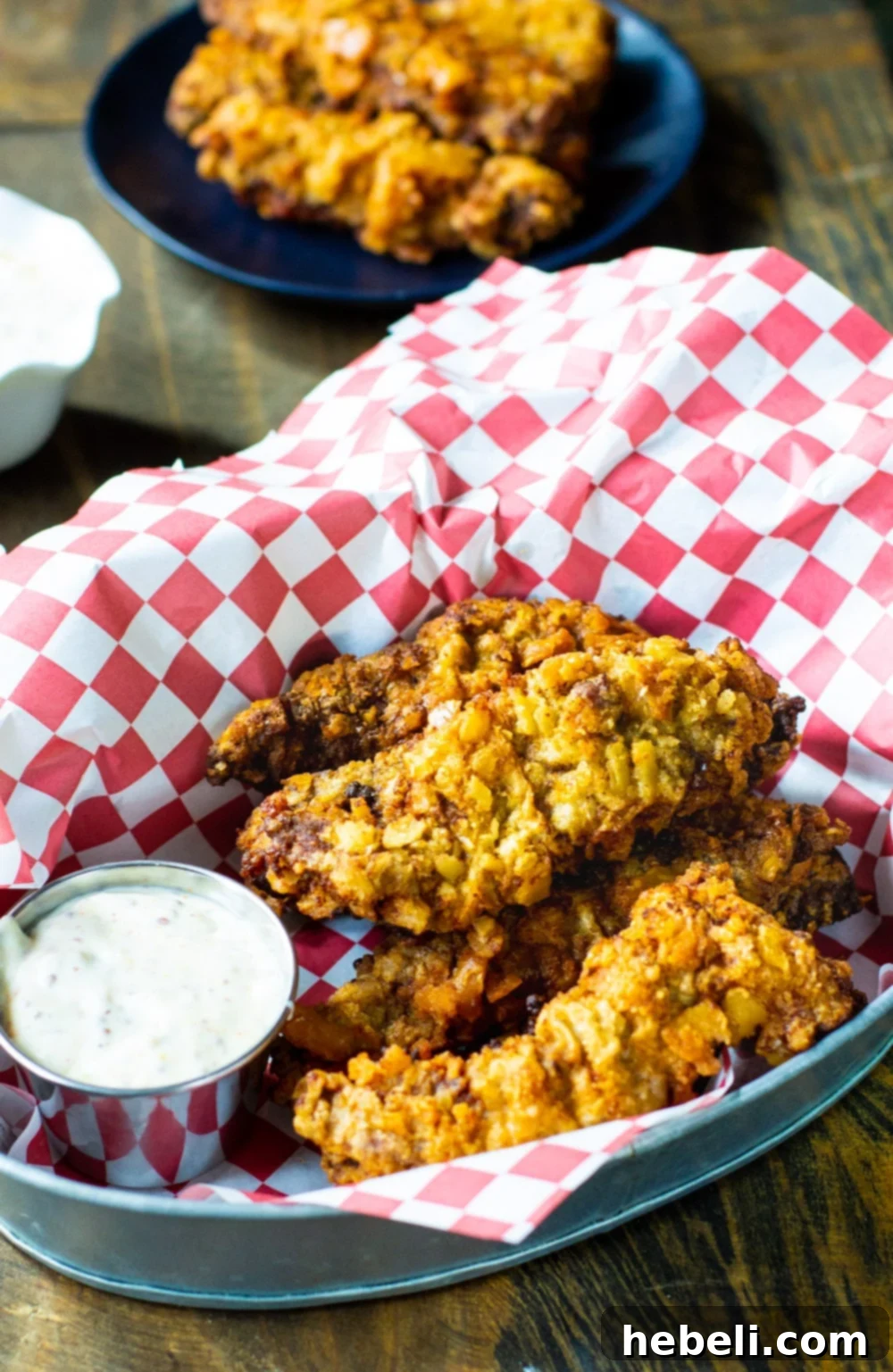 A close-up shot of golden-brown Fried Steak Fingers served in a basket, with a small dish of creamy Creole Mustard Sauce beside them.