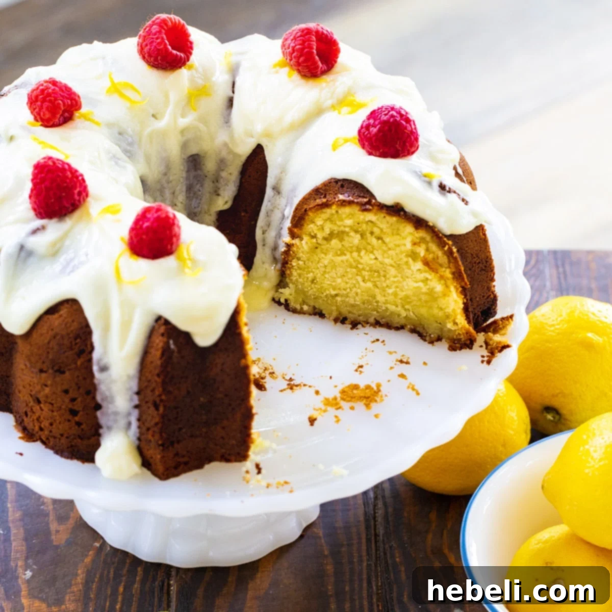 A perfectly baked Lemon Cream Cheese Pound Cake on an elegant cake stand, generously drizzled with a thick lemon glaze, ready to be sliced and served.