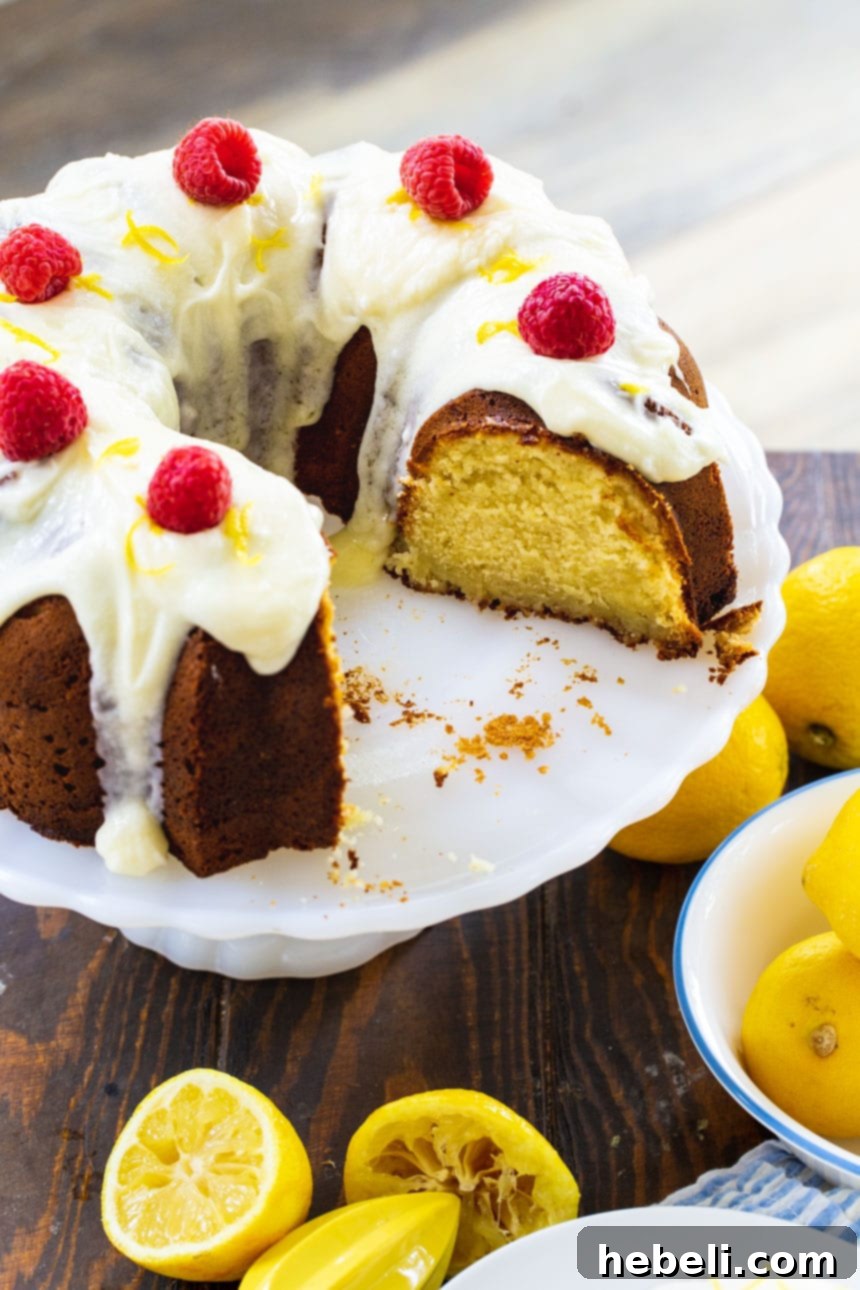 A close-up shot of a thick slice of Lemon Cream Cheese Pound Cake, showcasing its moist, creamy interior and the glistening lemon glaze.