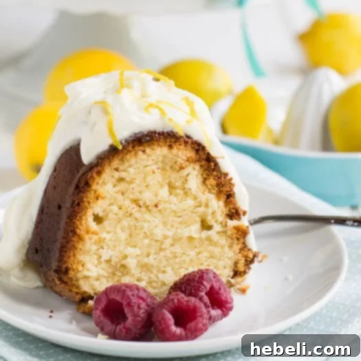 A whole Lemon Pound Cake lightly dusted with powdered sugar, sitting on a wooden cutting board, ready to be sliced and served.