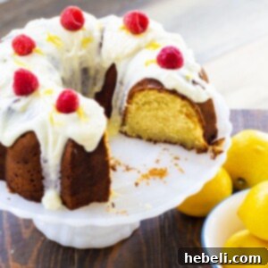 Lemon Pound Cake topped with fresh raspberries on a cake stand, enhancing its vibrant appeal.