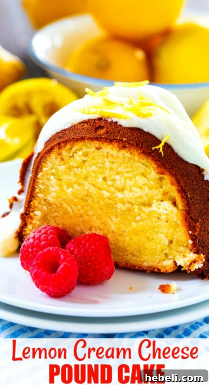 Close-up of a perfectly sliced Lemon Cream Cheese Pound Cake, featuring its moist interior and a thick layer of lemon glaze, adorned with three fresh raspberries on a white plate, ready to be savored.