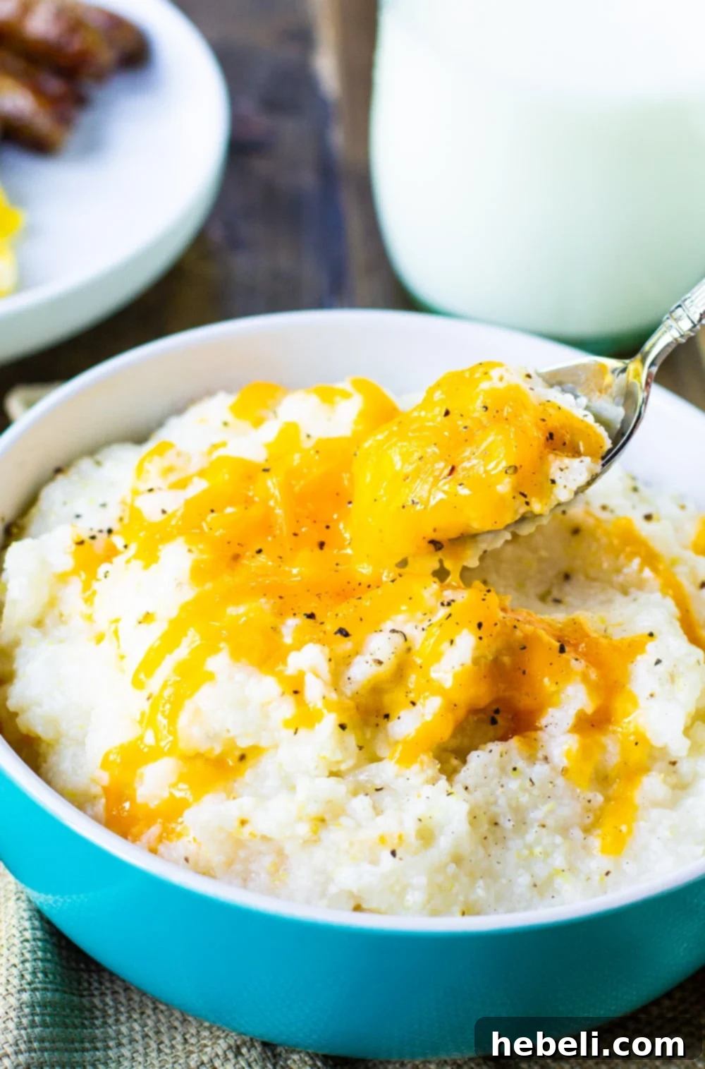 Spoonful of creamy Crockpot Grits being lifted from a bowl.