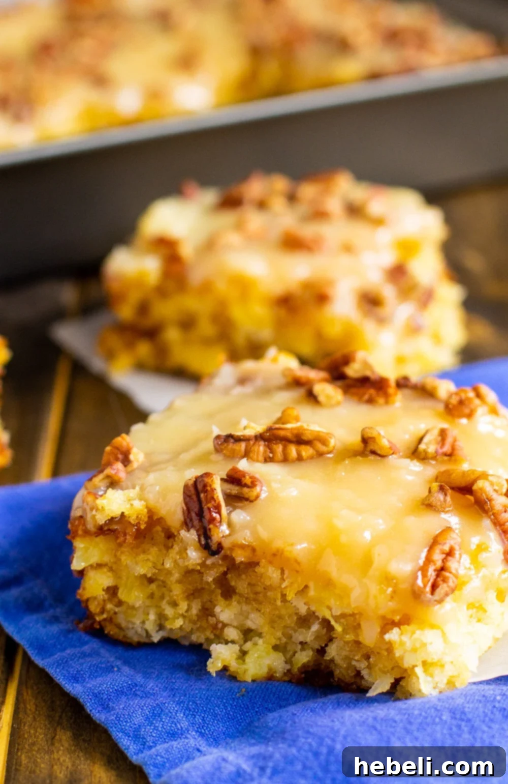 Two slices of Pineapple Sheet Cake served on a plate, showcasing the buttery coconut and pecan icing.