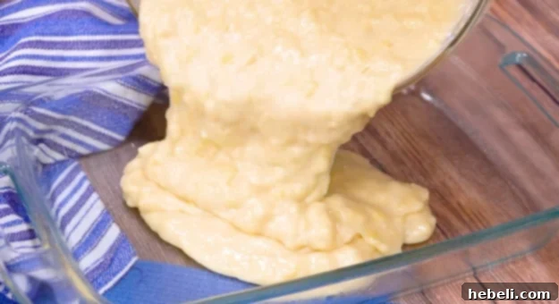 Pineapple cake batter being poured into a greased baking pan.