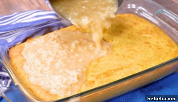 Warm coconut-pecan icing being poured evenly over a baked pineapple sheet cake.