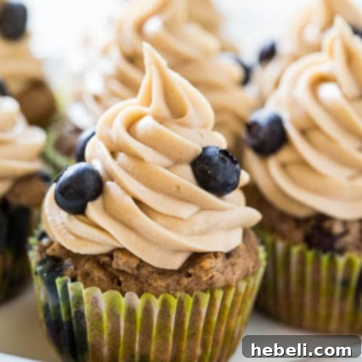 Luscious Blueberry Maple Cupcakes 4 Close-up of a single Blueberry Maple Cupcake with a swirl of maple frosting and fresh blueberries on top