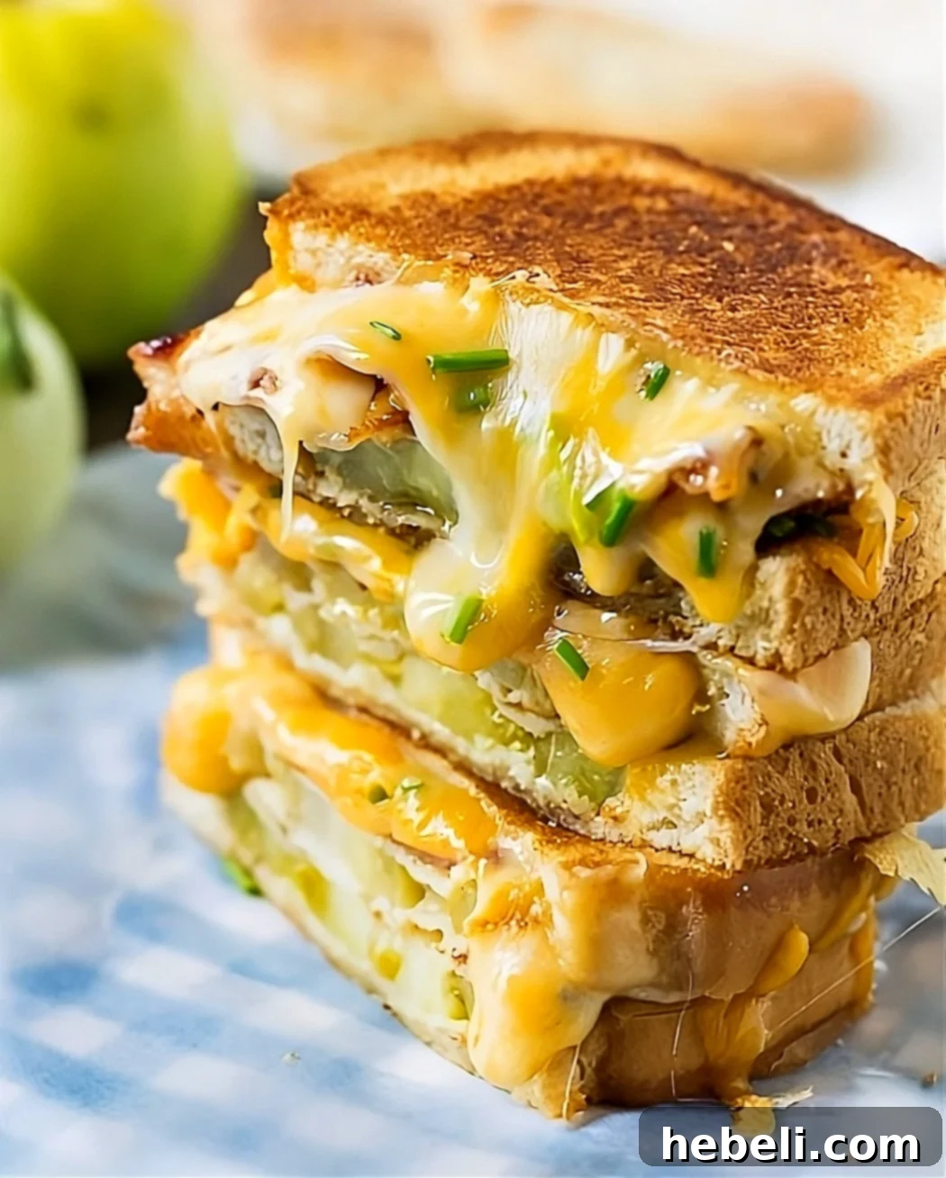 Grilled Cheese Sandwich with Bacon and Fried Green Tomatoes, cut in half, showing the rich, melted cheese dripping.