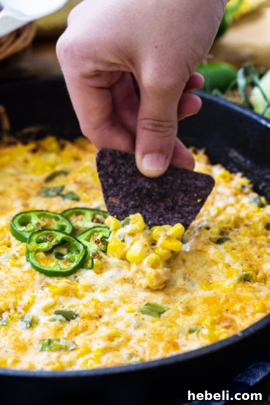 Hot Corn Dip with Jalapeños simmering in a cast iron pan, ready for its next serving.