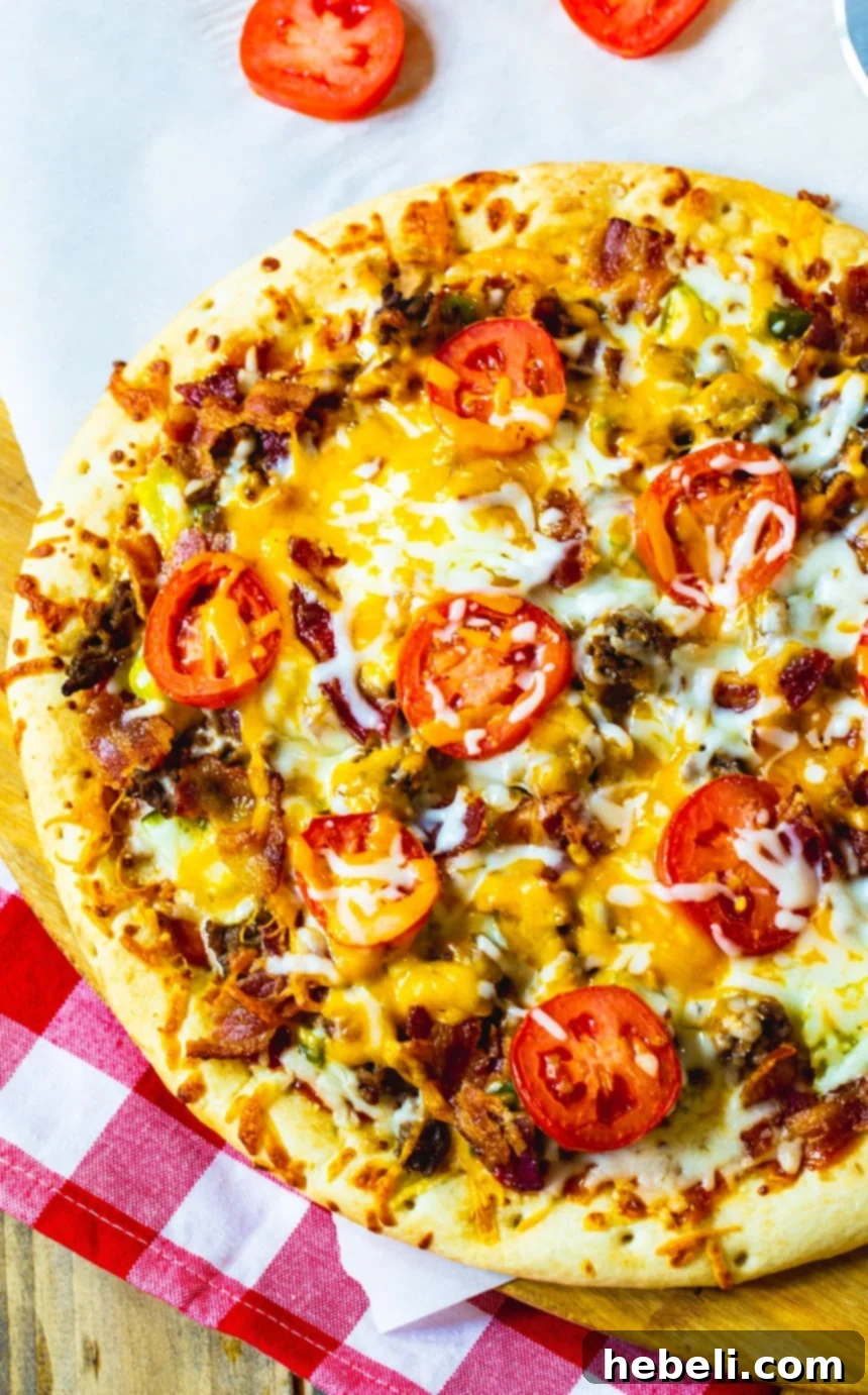 A large slice of homemade Cheeseburger Pizza on a wooden cutting board, garnished with fresh herbs.