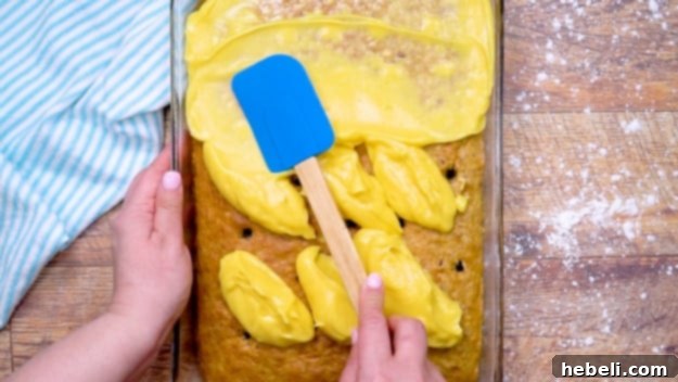 Tropical Hummingbird Poke Cake 6 Spreading the pudding mixture over the poked cake.