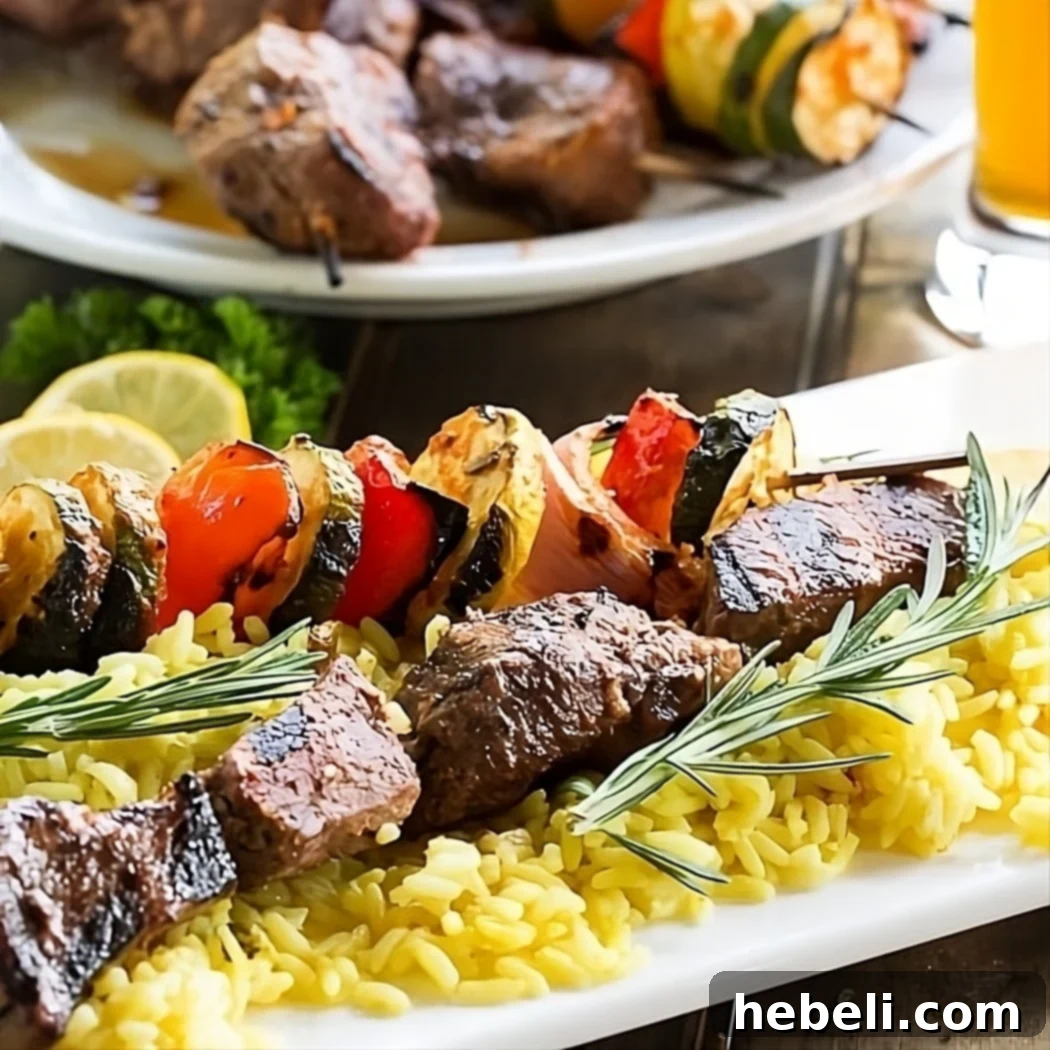 Flavorful Grilled Beef Skewers 2 Juicy grilled beef kabobs with vibrant red bell pepper, red onion, zucchini, and yellow squash over a bed of yellow rice.