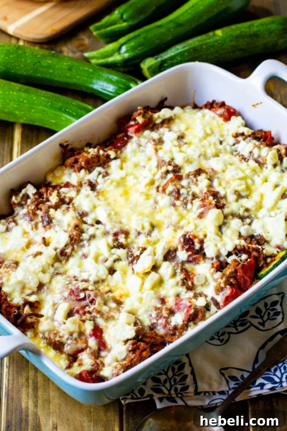 Creamy Zucchini Moussaka 3 Zucchini Moussaka in a casserole dish with fresh zucchini on the side, highlighting its main ingredient.