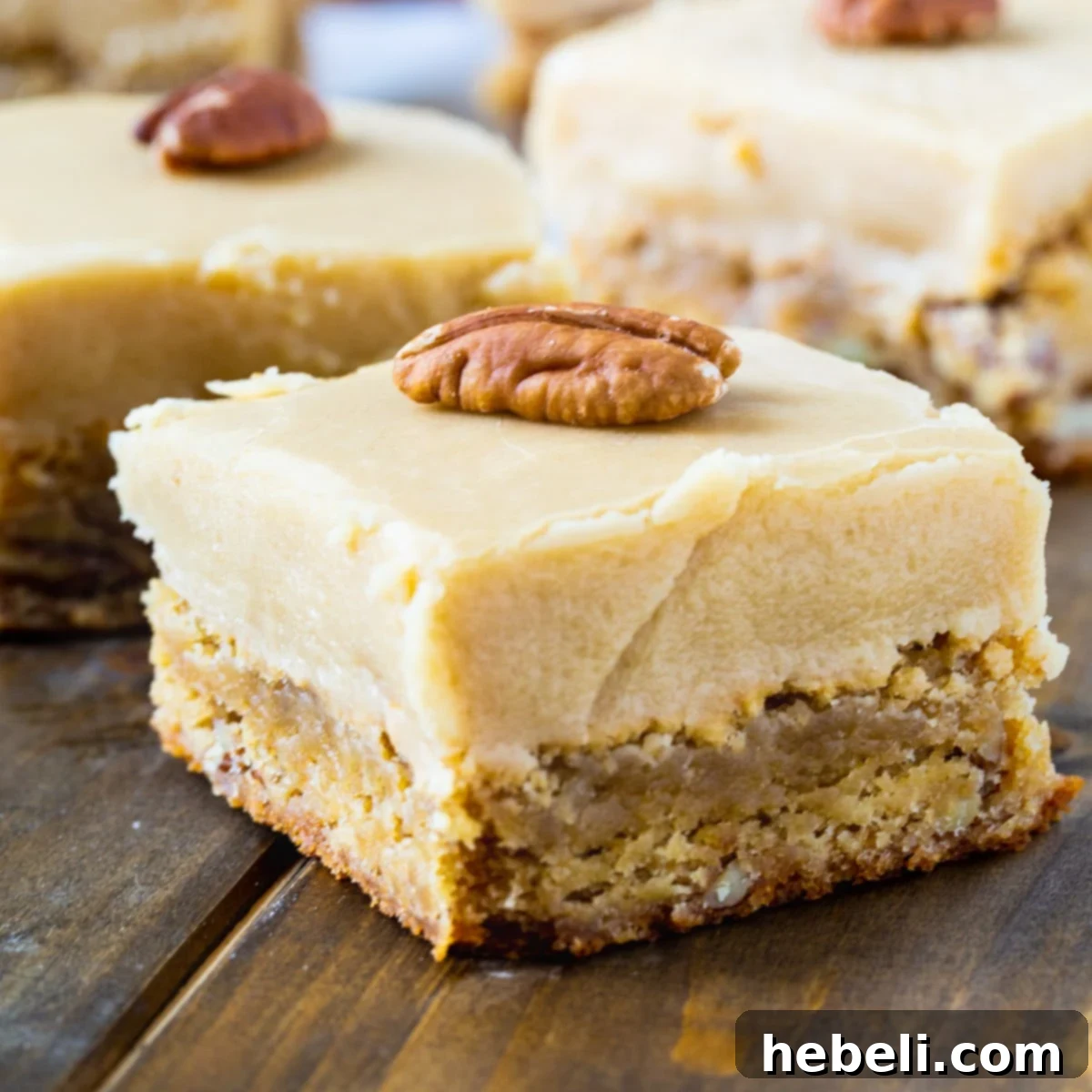 Butterscotch Blondies cut into squares with whole pecans on top, showcasing the thick frosting.