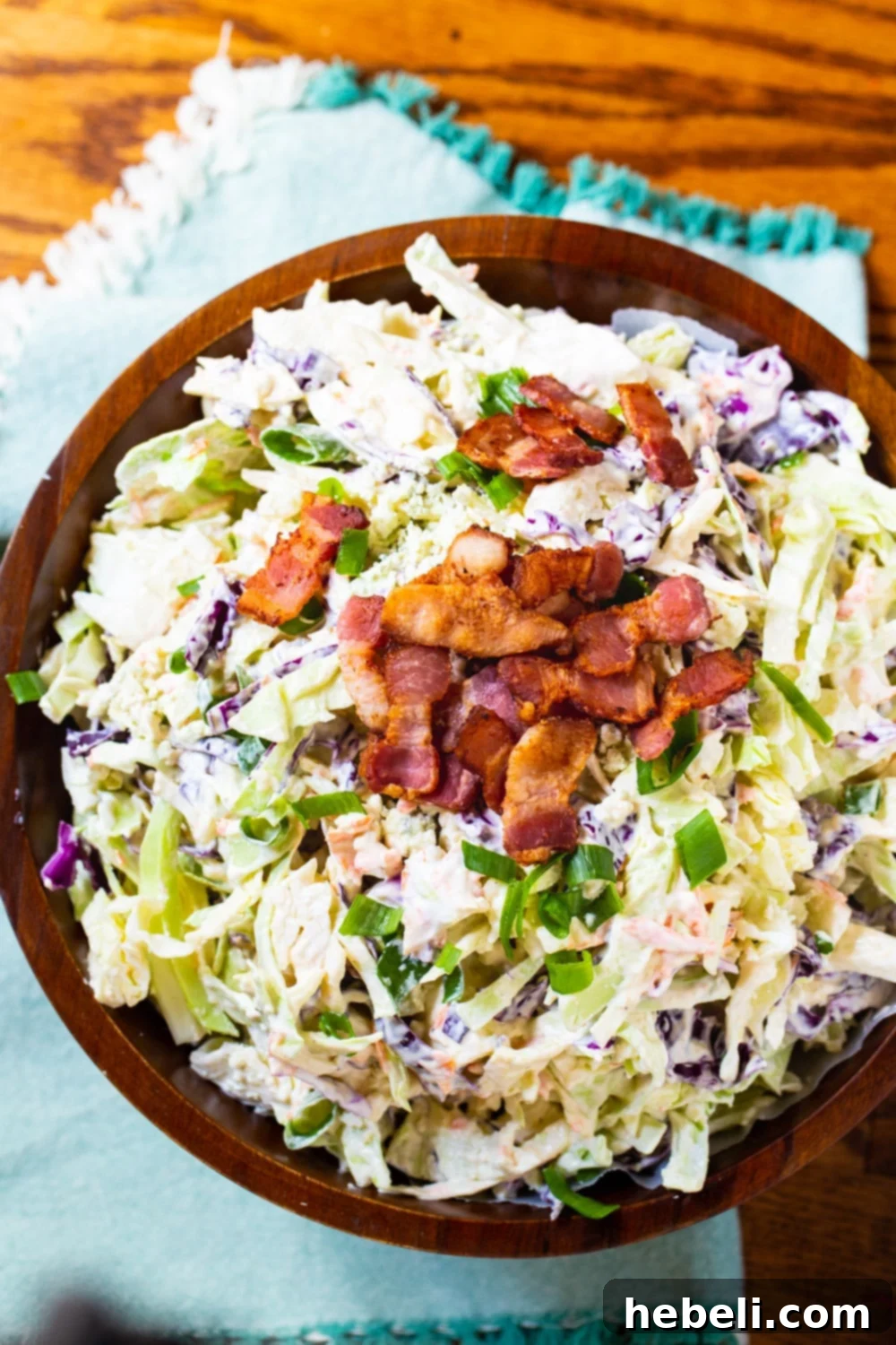 Tangy Blue Cheese Bacon Slaw 3 Coleslaw in a rustic wooden bowl, generously topped with crispy bacon crumbles, highlighting the enticing blend of ingredients.
