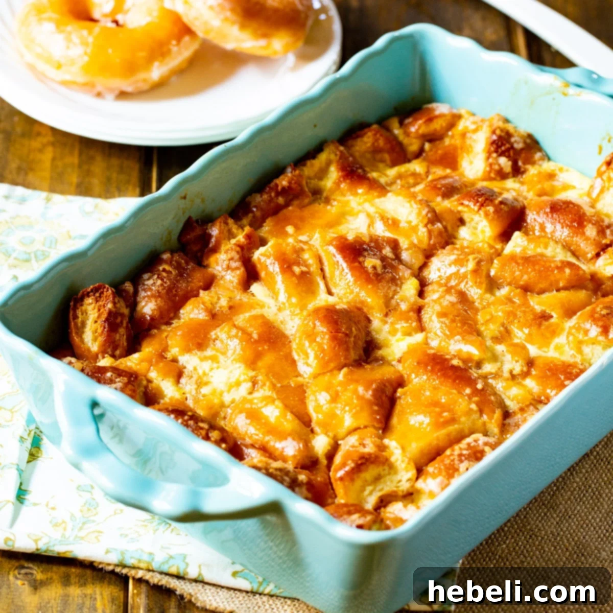 Krispy Kreme Bread Pudding in a baking dish, glistening with sauce.