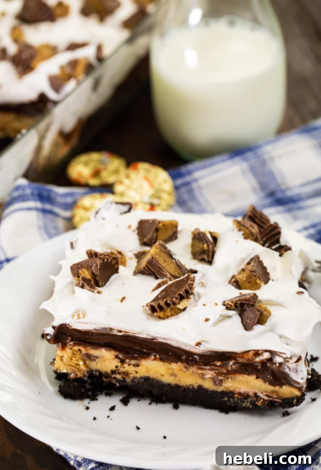 Decadent Peanut Butter Chocolate Stack 4 A close-up of a slice of Chocolate Peanut Butter Layer Dessert on a plate, showing the distinct layers and a topping of peanut butter cups.