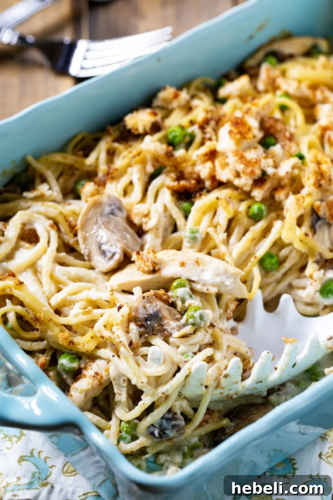 Comforting Turkey Tetrazzini Casserole 3 Turkey Tetrazzini being scooped out of a blue casserole dish, showing the creamy texture.