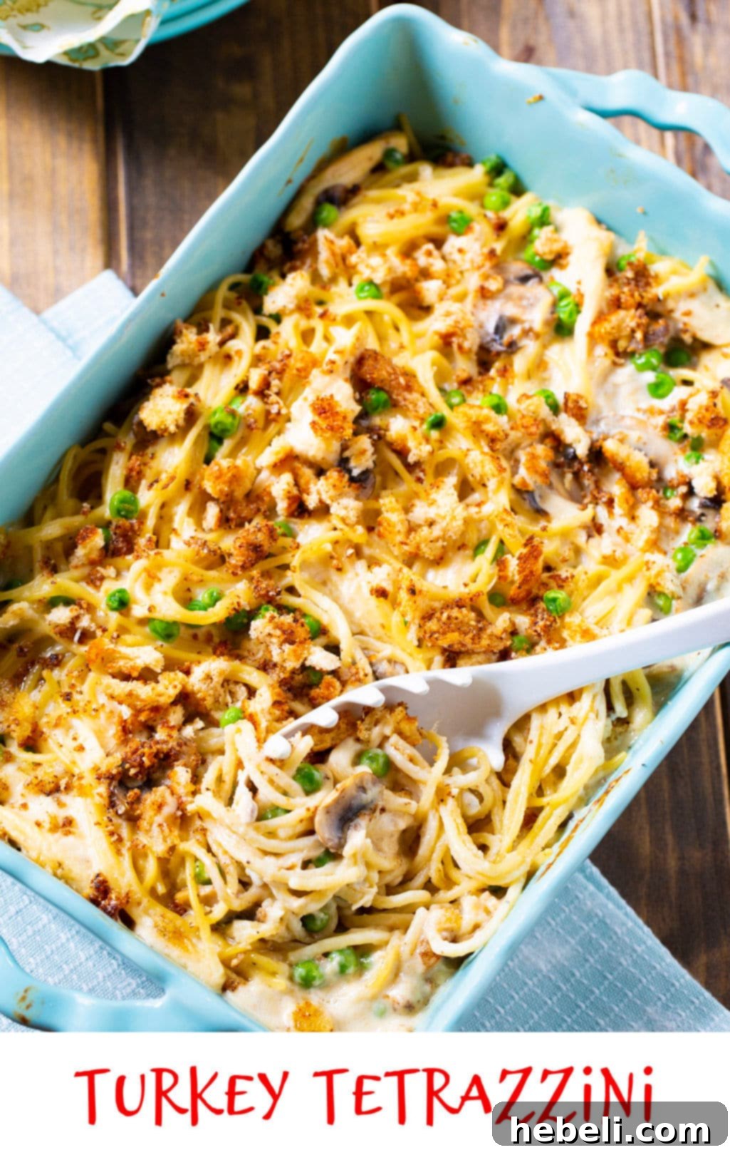 Comforting Turkey Tetrazzini Casserole 5 Baked Turkey Tetrazzini in a blue casserole dish with a golden-brown topping.