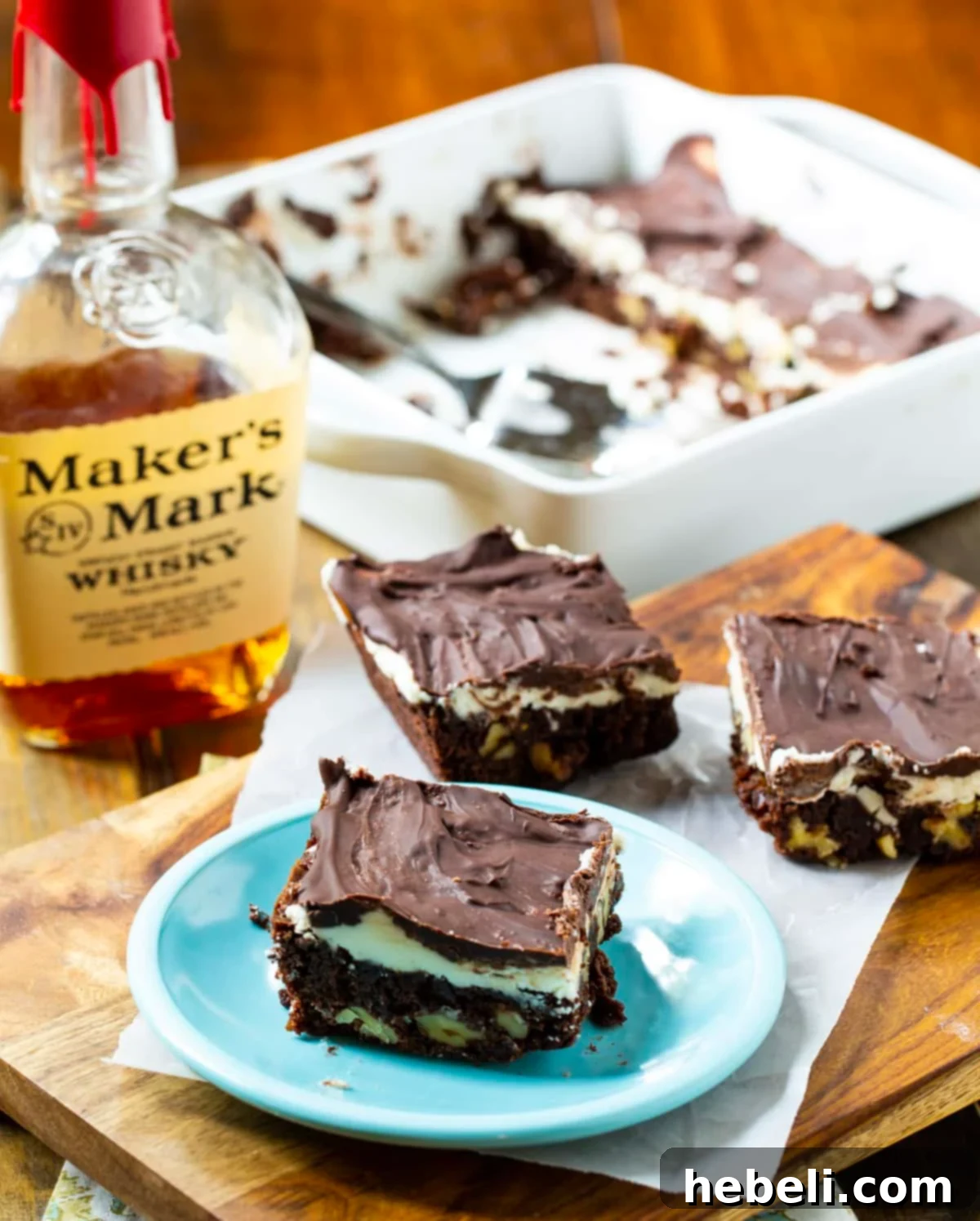 Double Frosted Bourbon Brownies meticulously arranged on a rustic wood cutting board, highlighting their beautiful double frosting.