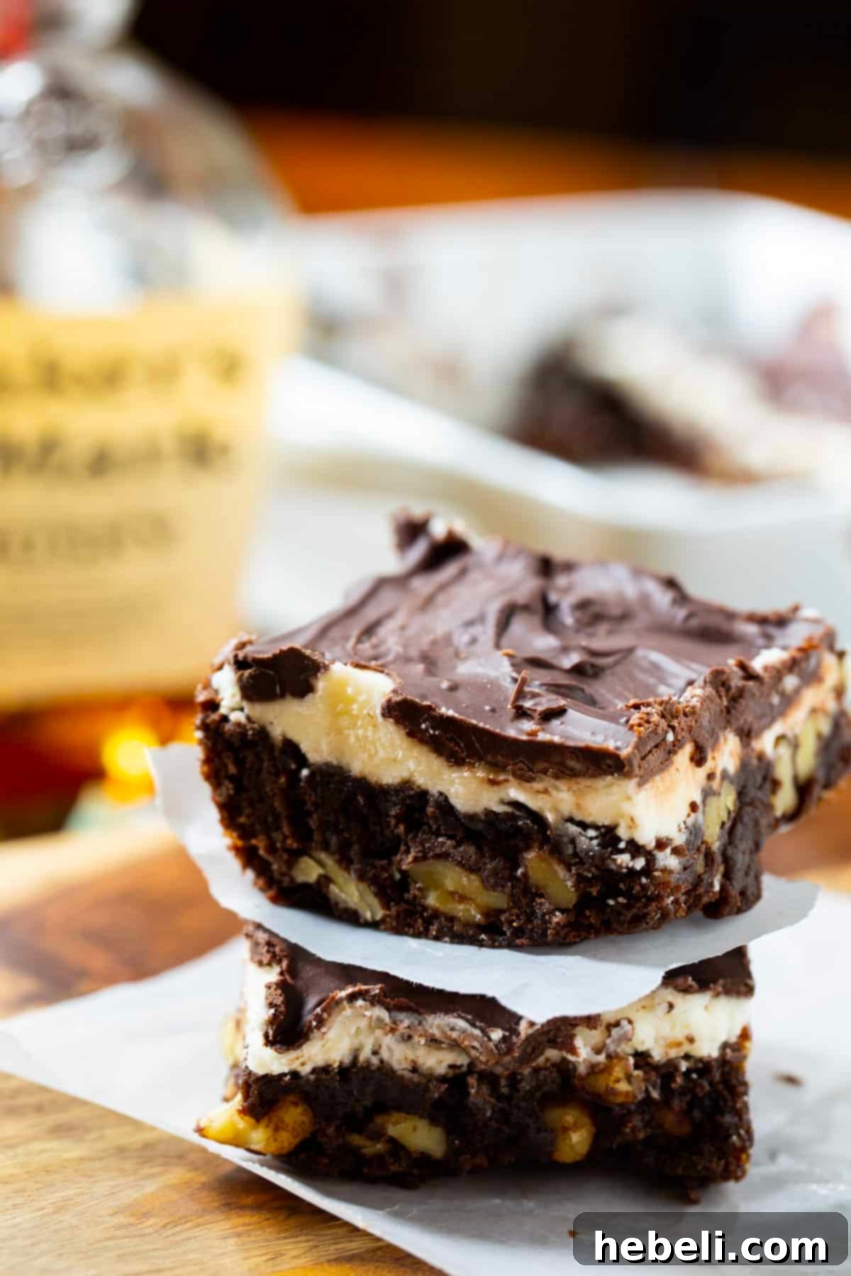 Two exquisitely frosted bourbon brownies stacked, highlighting the rich chocolate and creamy white layers.