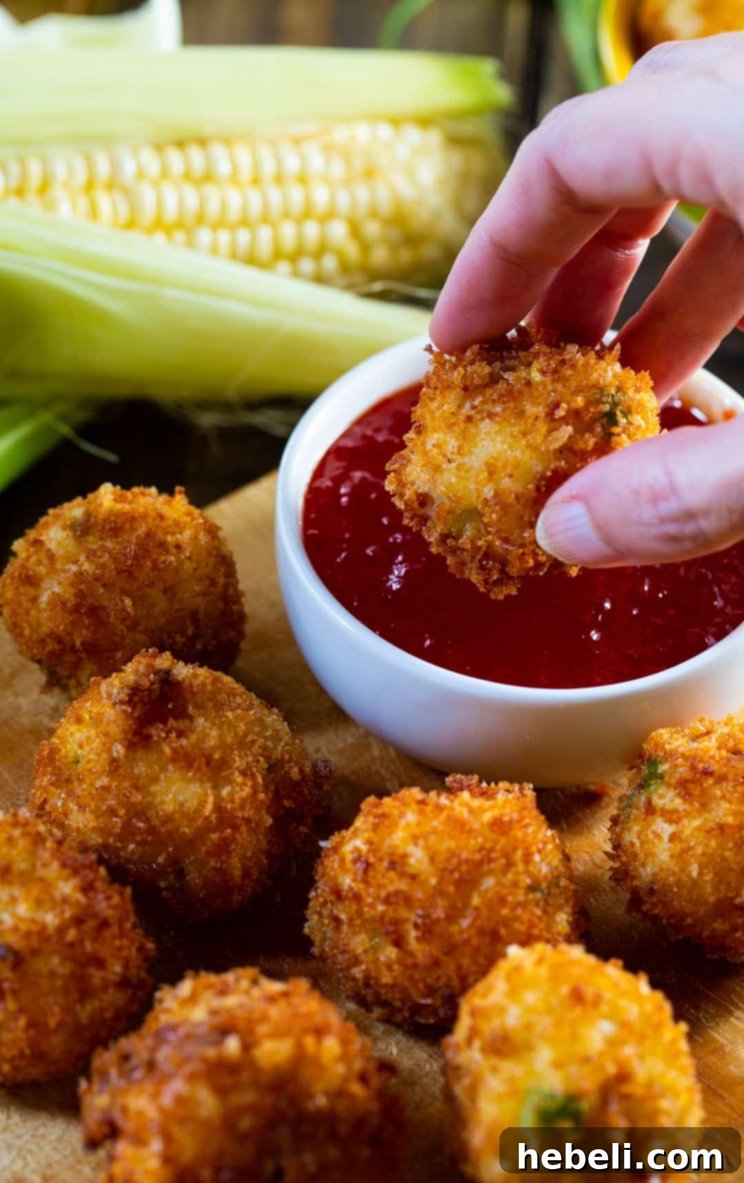 Hand dipping fritter in sauce.