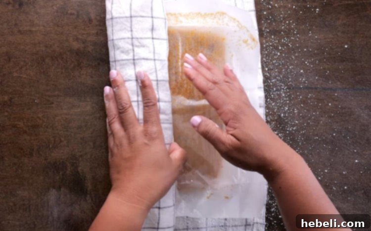 Carefully rolling the warm pumpkin cake, along with its sugared towel, into a tight cylindrical shape.