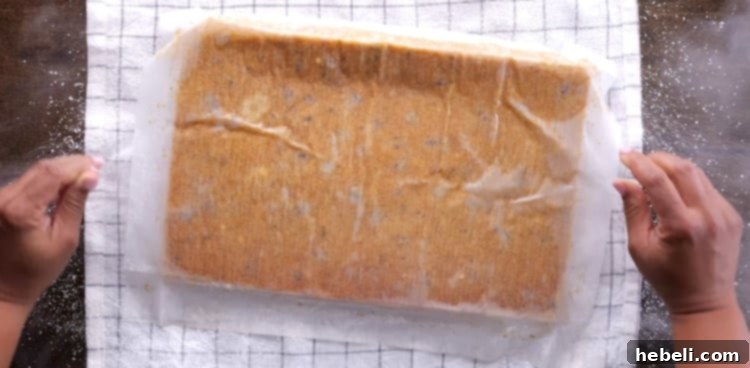 Flipping the freshly baked, warm pumpkin cake onto a powdered sugar-dusted kitchen towel.