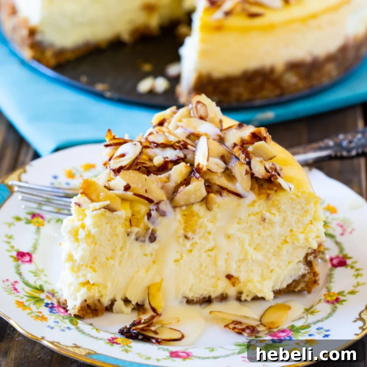 A perfectly sliced piece of Amaretto Cheesecake on an elegant china plate, showcasing its creamy texture and almond topping.