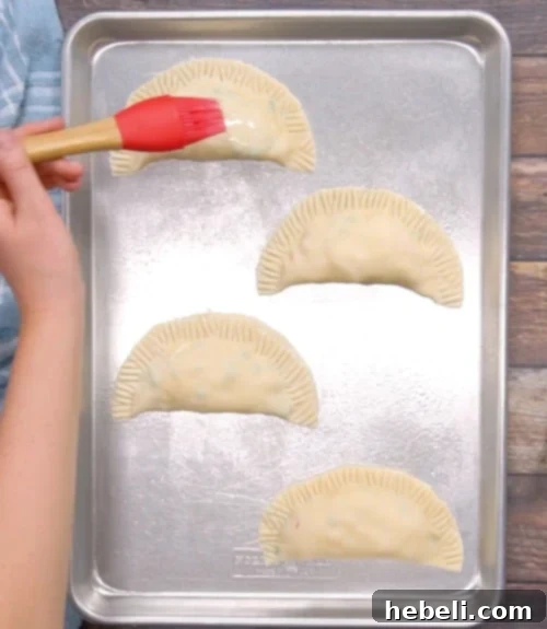 Brushing the tops of chicken pot pie turnovers with egg wash.
