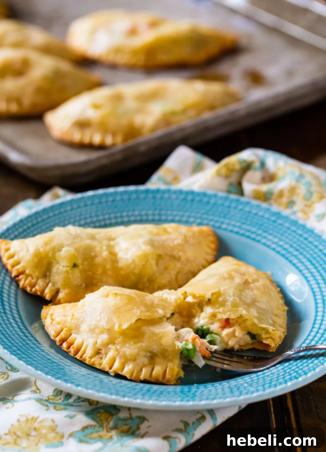 A fork taking a piece out of a delicious Chicken Pot Pie Turnover, revealing the creamy filling.