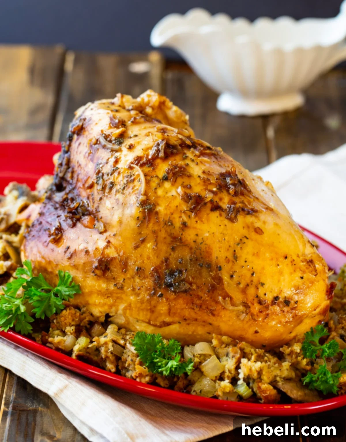 Juicy Slow Cooker Turkey Breast 3 A perfectly cooked whole turkey breast resting atop a bed of aromatic stuffing on a elegant serving platter.