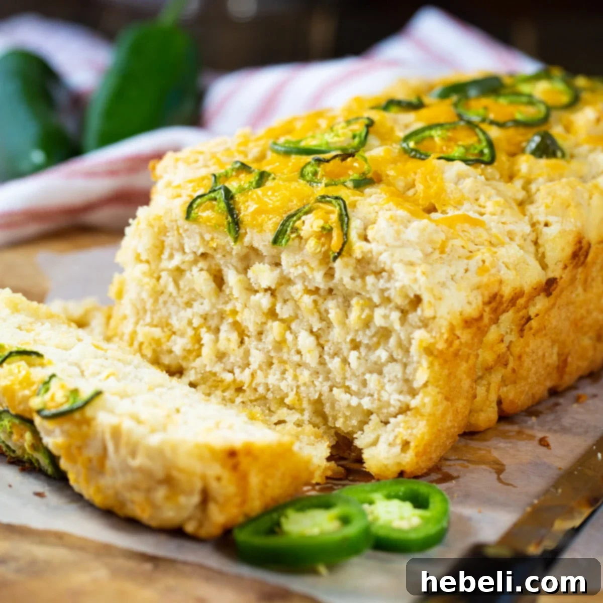A freshly baked loaf of Jalapeno Beer Bread with a slice cut, showing the moist, cheesy interior.