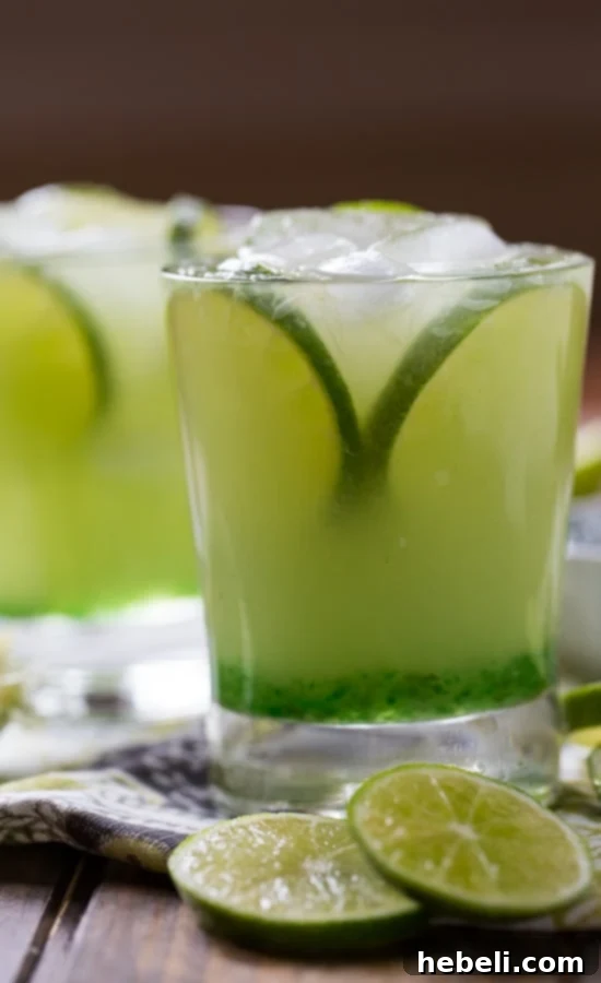 A hand holding a freshly squeezed lime over a bowl of lime halves
