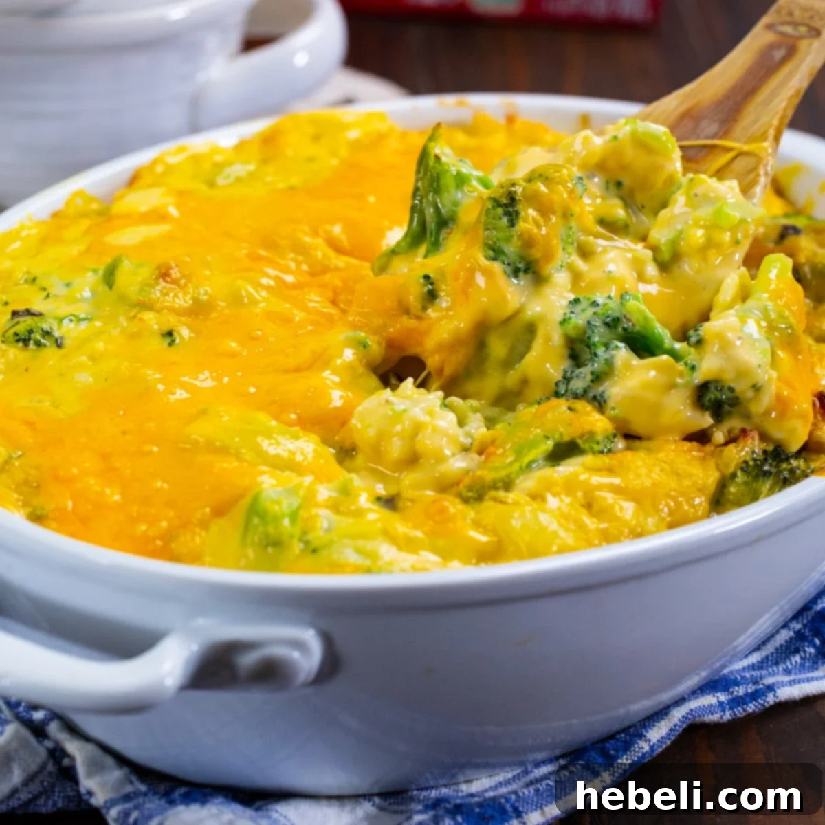 Wooden spoon scooping up Cheesy Broccoli Rice Casserole, highlighting its creamy texture.