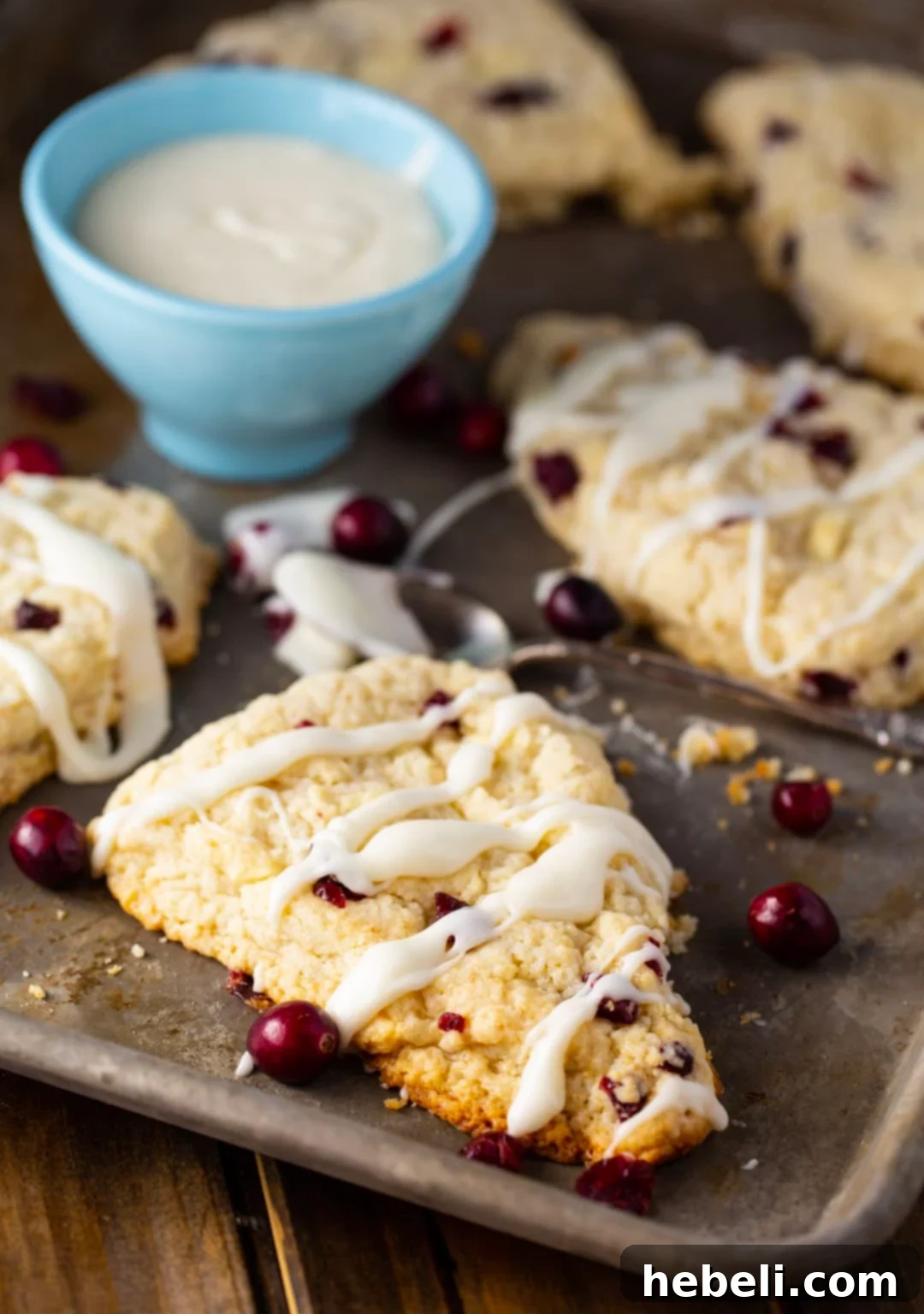 White Chocolate Cranberry Bliss Scones 3 A selection of Cranberry White Chocolate Scones ready to be glazed, next to a bowl of vanilla glaze.