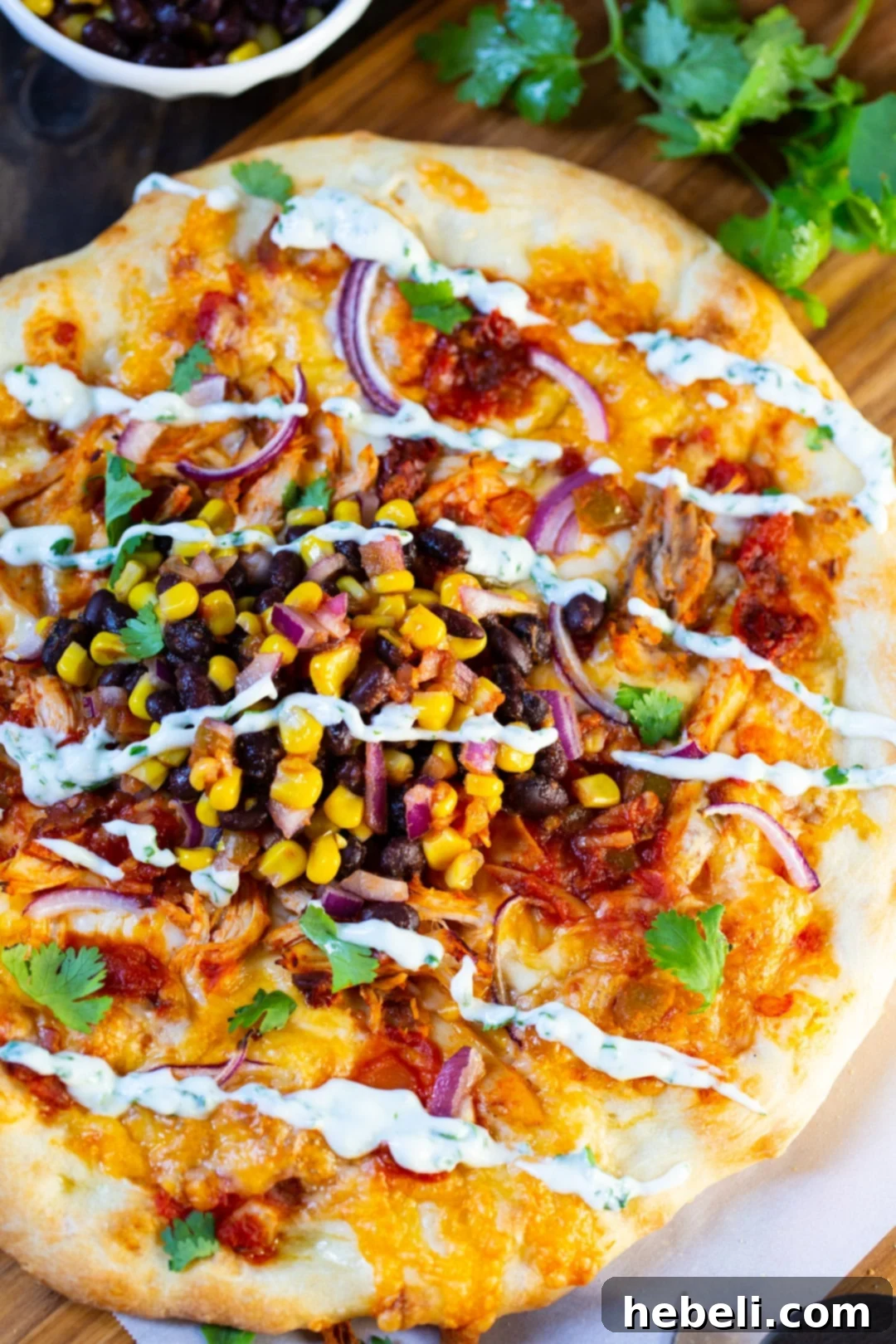 Smoky Chipotle Chicken Pizza 3 Overhead view of a whole, freshly baked Chipotle Chicken Pizza, beautifully arranged with a medley of toppings including black bean-corn salsa and cilantro-lime cream drizzle.