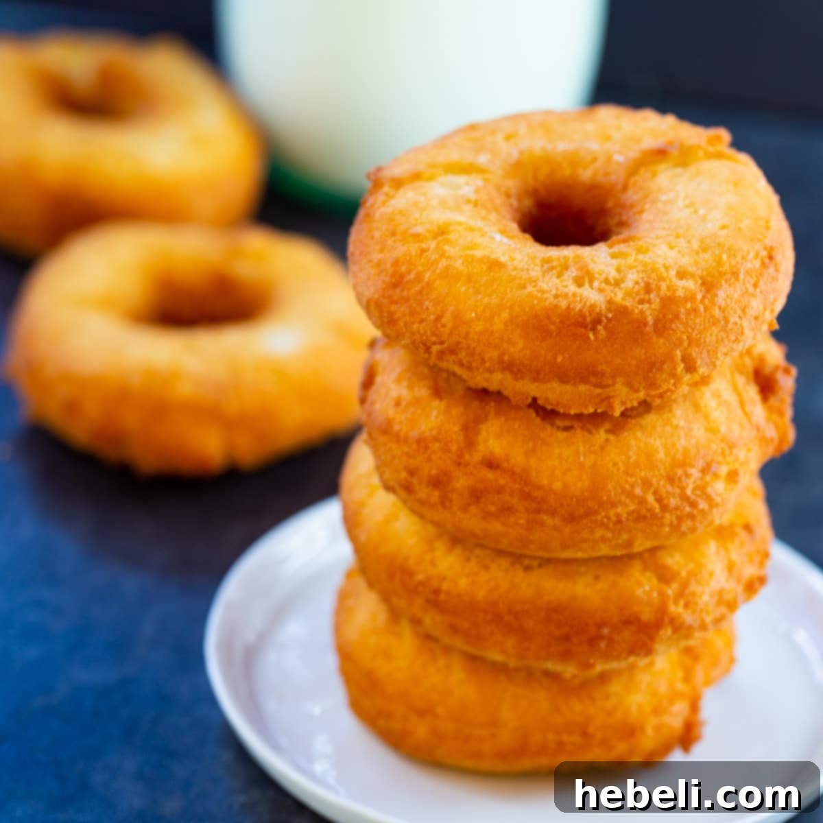 Four Old-Fashioned Buttermilk Doughnuts stacked on a small plate, golden brown and inviting.