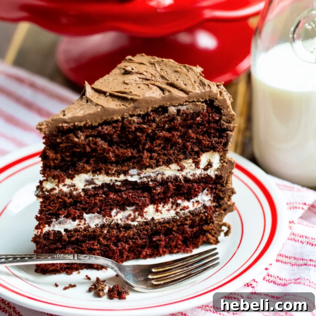 A perfectly sliced piece of three-layer Chocolate Cake with Cream Filling, served elegantly on a plate, ready to be enjoyed.