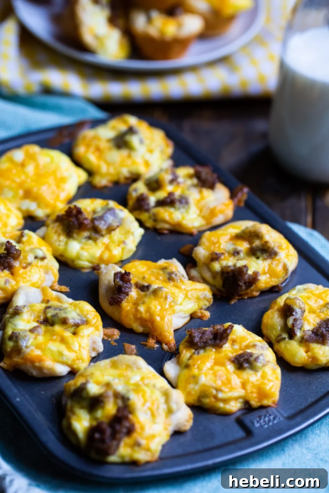 Mini Sausage Biscuit Cups baking in a muffin tin, showing the golden biscuit edges.