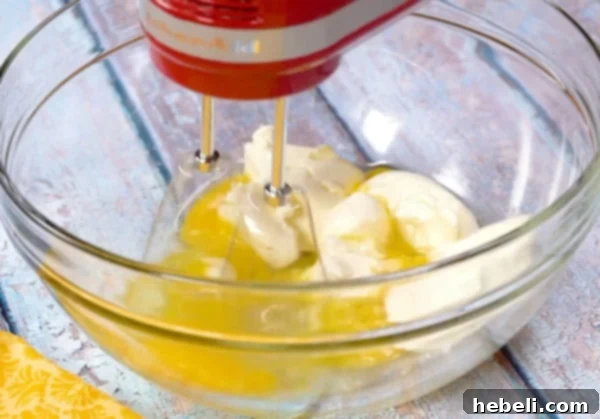 Beating cream cheese and eggs together until smooth in a mixing bowl.