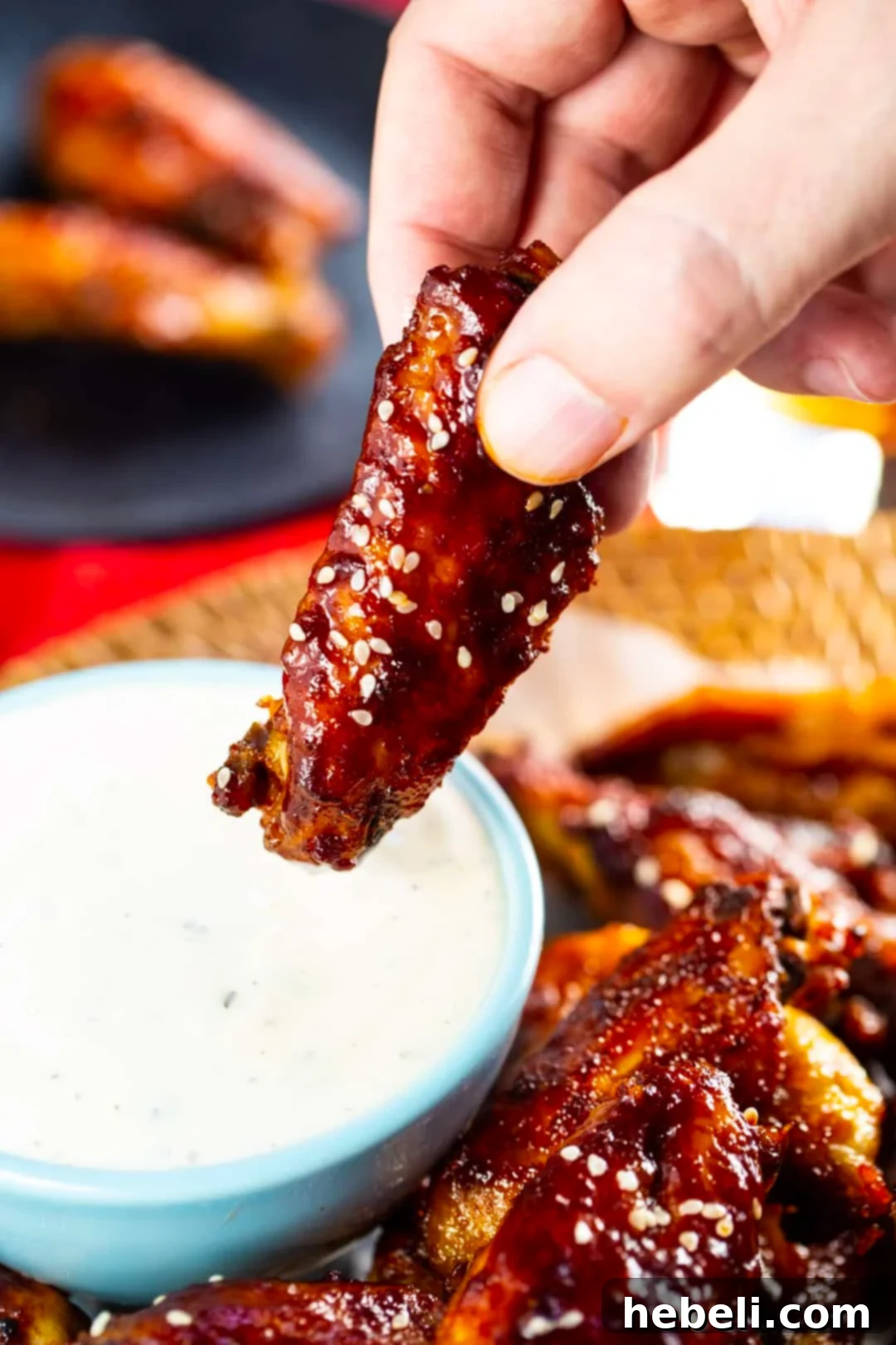 Slow Cooker Sweet Heat Glazed Wings 5 Hand dipping wing into ranch dressing.