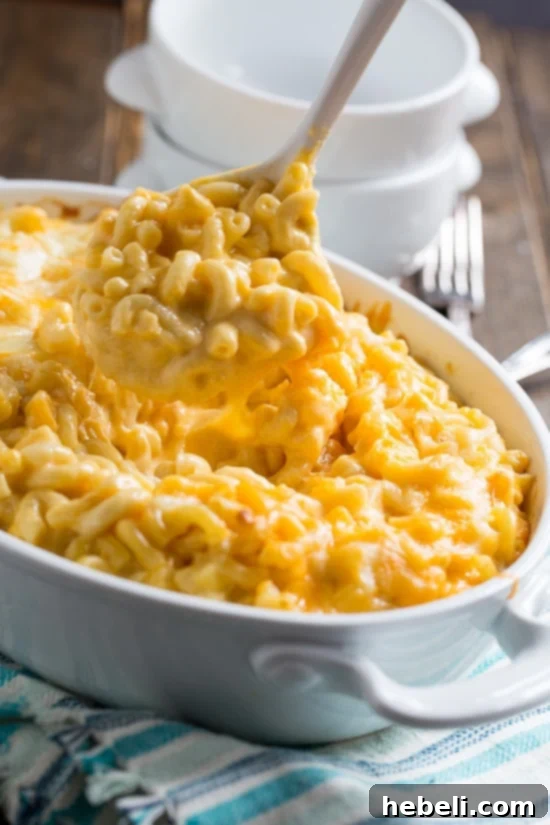 Silken Mac and Cheese 4 A serving spoon lifting a generous portion of Super Creamy Mac and Cheese, highlighting its stretchy, melty cheese and perfectly cooked elbow macaroni.